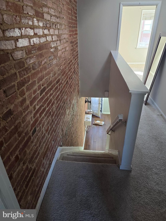 123 N Belnord Ave, Baltimore, MD 21224 - stairway featuring carpet floors, brick wall, and baseboards