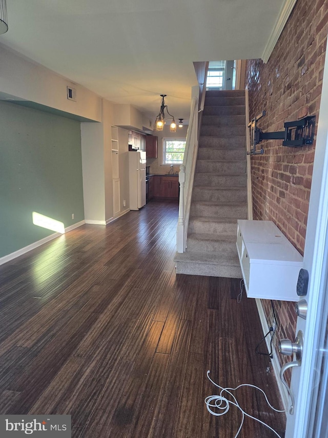123 N Belnord Ave, Baltimore, MD 21224 - stairs featuring wood finished floors, brick wall, baseboards, and a chandelier