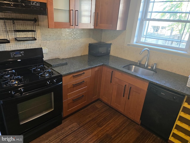 kitchen with sink, black appliances, tasteful backsplash, dark stone countertops, and dark hardwood / wood-style flooring