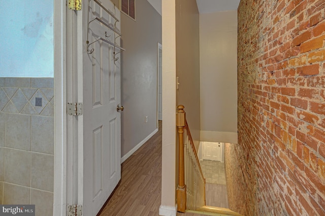 hall featuring brick wall and hardwood / wood-style floors