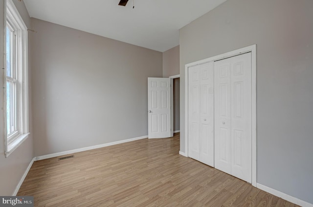 unfurnished bedroom with ceiling fan, multiple windows, and light wood-type flooring