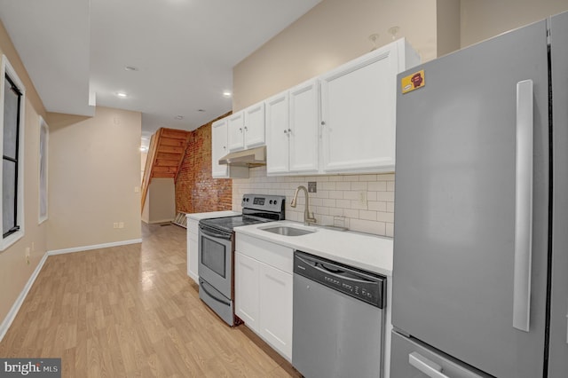 kitchen with white cabinets, backsplash, appliances with stainless steel finishes, light hardwood / wood-style flooring, and sink