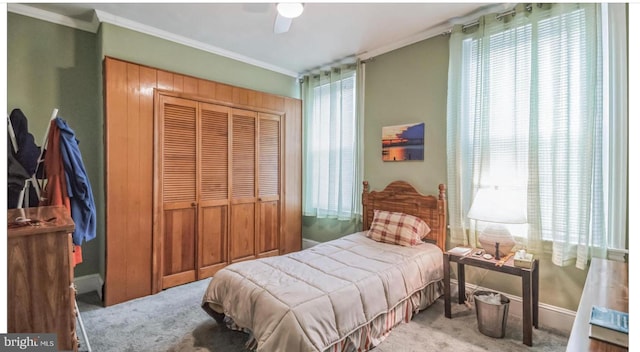 bedroom with a closet, ceiling fan, crown molding, and carpet flooring