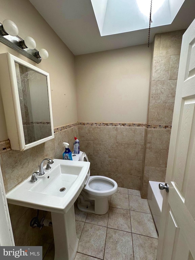 bathroom with a bath, toilet, tile walls, and a skylight