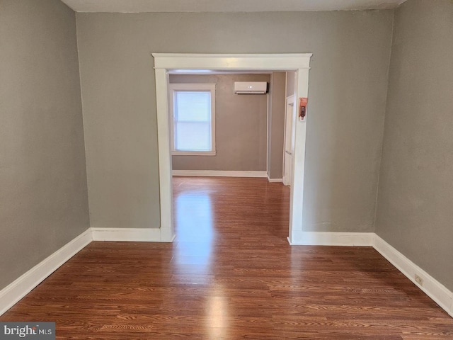 spare room featuring a wall unit AC and dark wood-type flooring