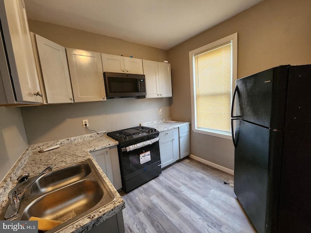 kitchen featuring white cabinetry, black appliances, sink, and light wood-type flooring