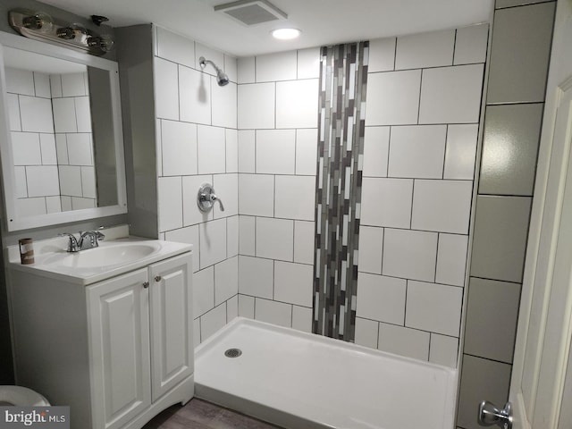 bathroom with vanity, tiled shower, and hardwood / wood-style floors