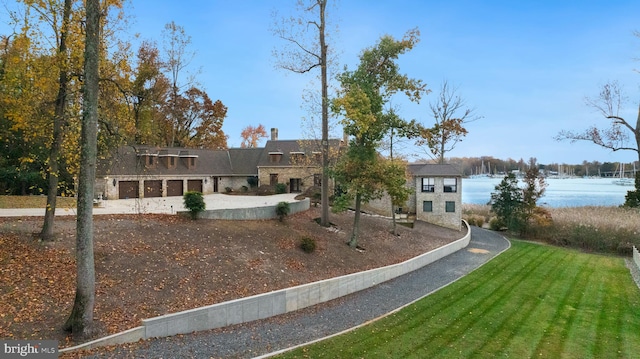 view of front of home with a water view, a front yard, and a garage