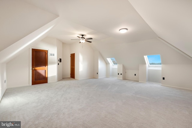 bonus room with light carpet, vaulted ceiling with skylight, and ceiling fan