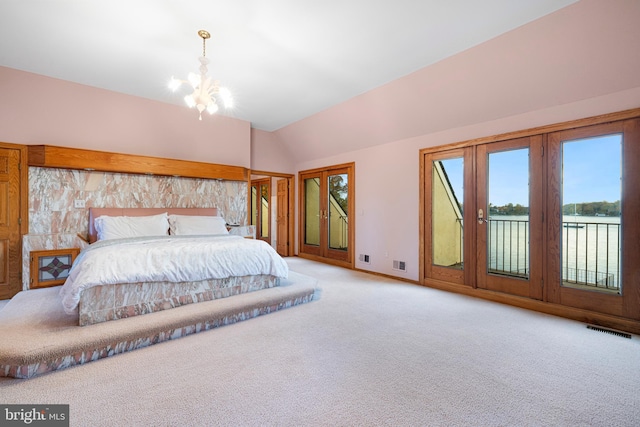 carpeted bedroom with access to exterior, a water view, a chandelier, and vaulted ceiling