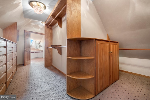 spacious closet featuring light colored carpet and lofted ceiling