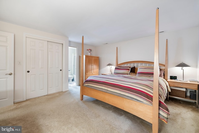 bedroom with ensuite bathroom, light colored carpet, and a closet