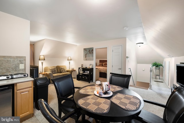 carpeted dining room featuring vaulted ceiling