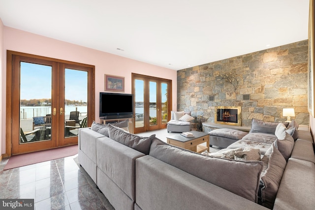 living room with a stone fireplace and french doors