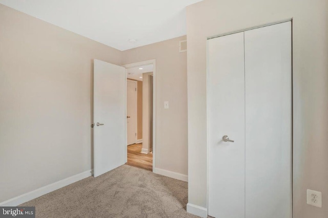 unfurnished bedroom featuring a closet and light carpet