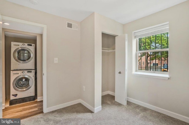 laundry room with stacked washer and dryer and light colored carpet