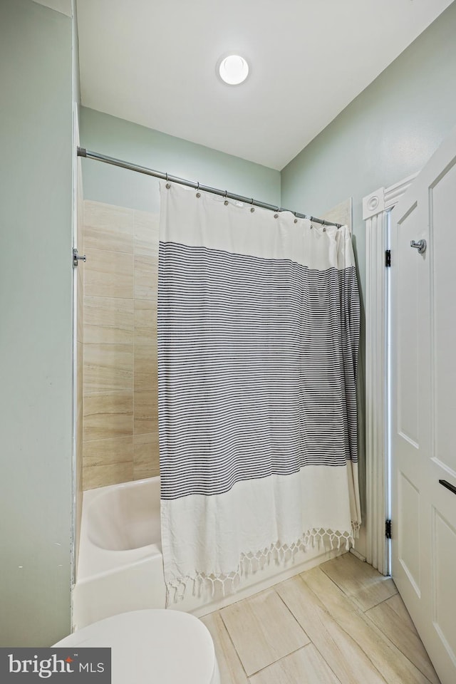 bathroom with shower / tub combo with curtain and toilet