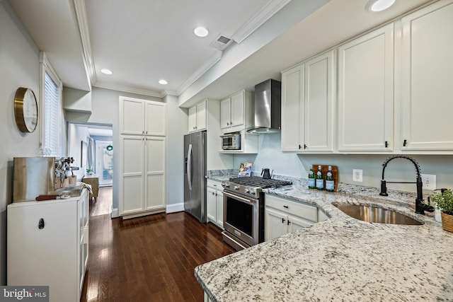 kitchen featuring wall chimney exhaust hood, white cabinets, appliances with stainless steel finishes, light stone counters, and dark hardwood / wood-style flooring