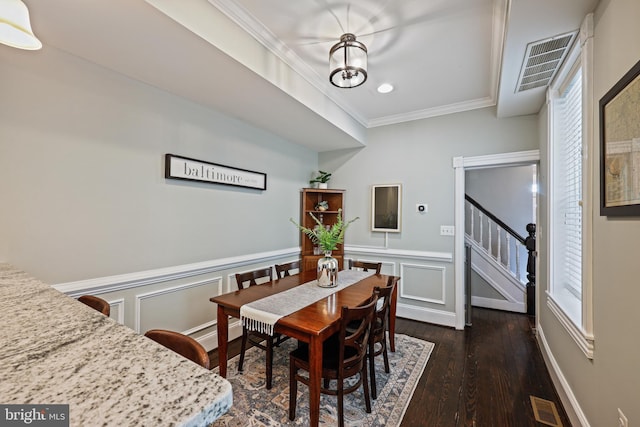 dining area featuring dark wood-type flooring, crown molding, and a notable chandelier