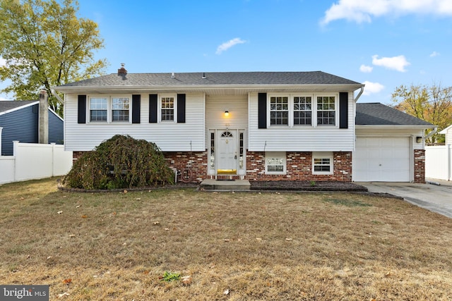 raised ranch with a front lawn and a garage