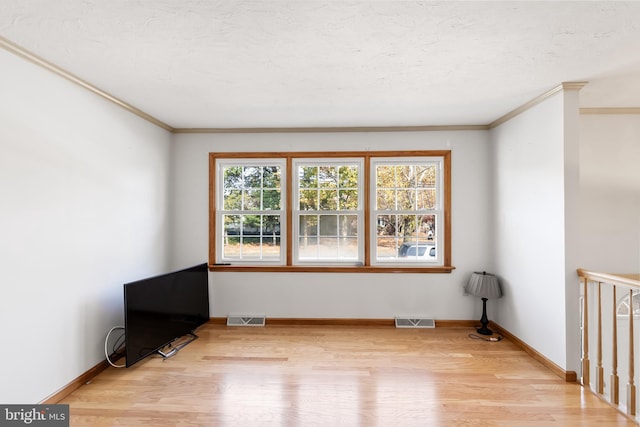 empty room with crown molding and light wood-type flooring