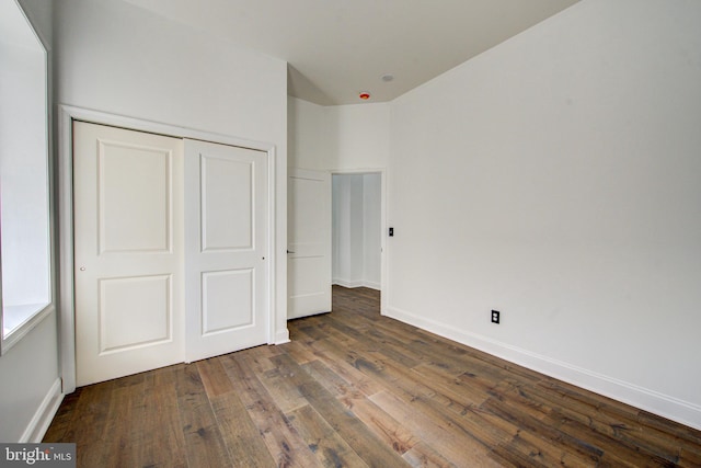 unfurnished bedroom with a closet and dark hardwood / wood-style flooring