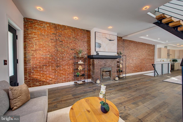 living room with brick wall, a fireplace, and wood-type flooring