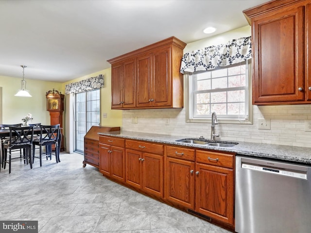 kitchen with tasteful backsplash, light stone countertops, stainless steel dishwasher, and sink