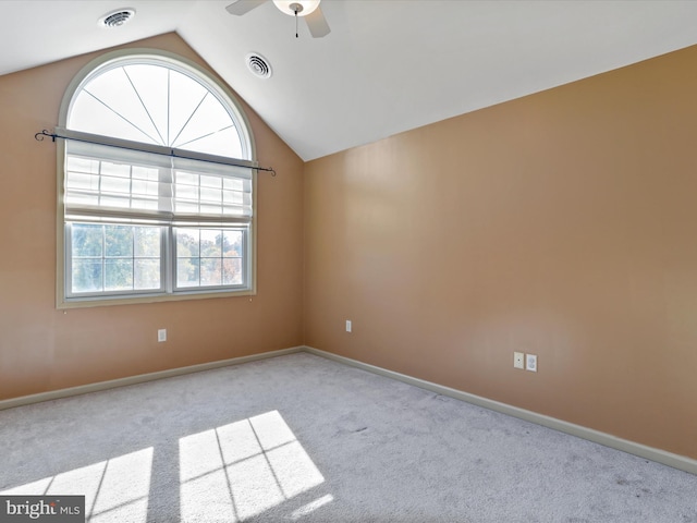 carpeted spare room featuring a healthy amount of sunlight, ceiling fan, and vaulted ceiling