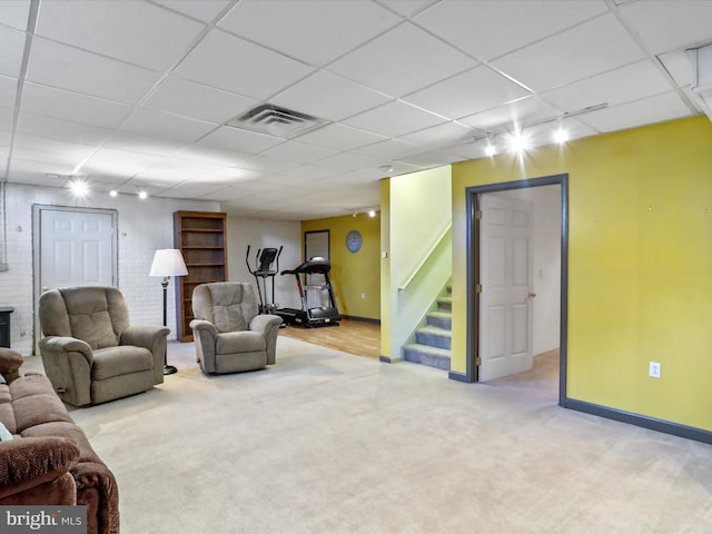 living room with a paneled ceiling, carpet, and a brick fireplace