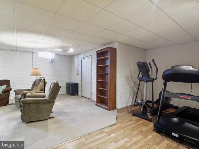 workout area with a drop ceiling and wood-type flooring