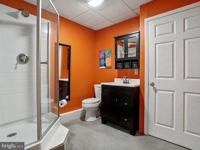 bathroom featuring vanity, toilet, a shower with shower door, and a drop ceiling