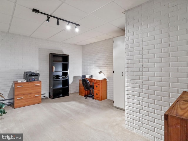 home office featuring a baseboard heating unit, light colored carpet, brick wall, and rail lighting