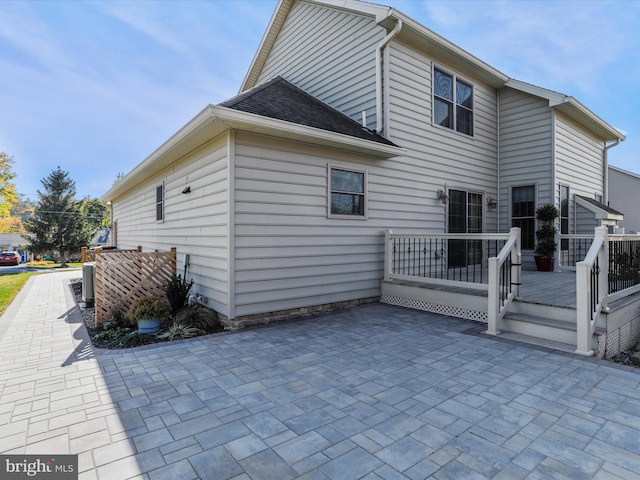 rear view of property with a wooden deck and a patio