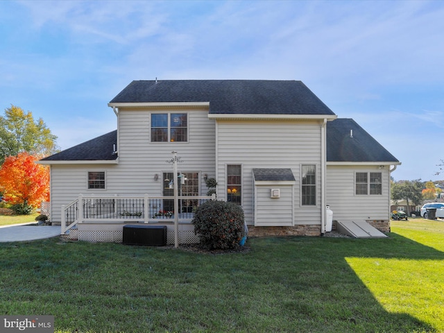 rear view of house with cooling unit, a deck, and a lawn