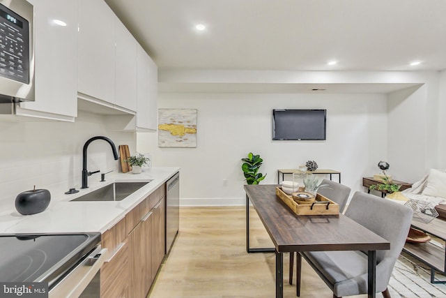 kitchen featuring white cabinetry, stainless steel appliances, sink, and light hardwood / wood-style flooring