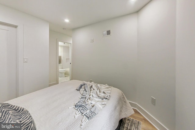 bedroom with ensuite bath and wood-type flooring