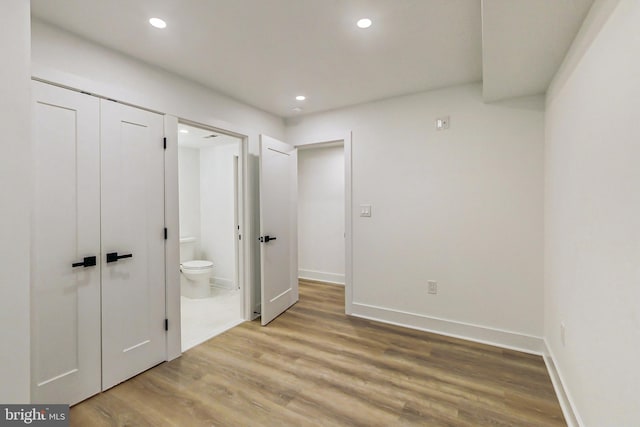 unfurnished bedroom featuring ensuite bathroom, light wood-type flooring, and a closet