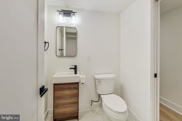 bathroom featuring wood-type flooring, vanity, and toilet