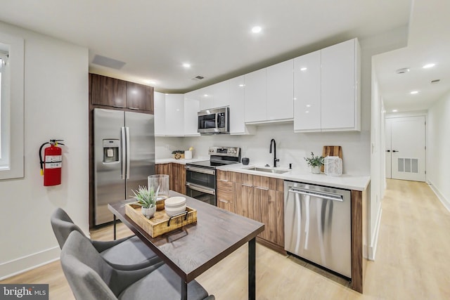 kitchen with white cabinetry, sink, light hardwood / wood-style floors, and stainless steel appliances