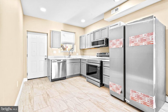 kitchen featuring appliances with stainless steel finishes, sink, and gray cabinets