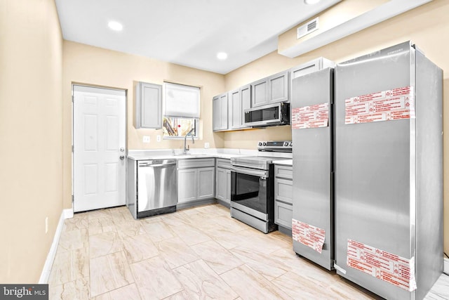 kitchen with appliances with stainless steel finishes, light countertops, baseboards, marble finish floor, and gray cabinets