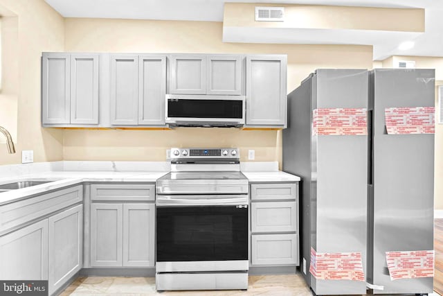 kitchen with gray cabinetry, stainless steel appliances, and sink