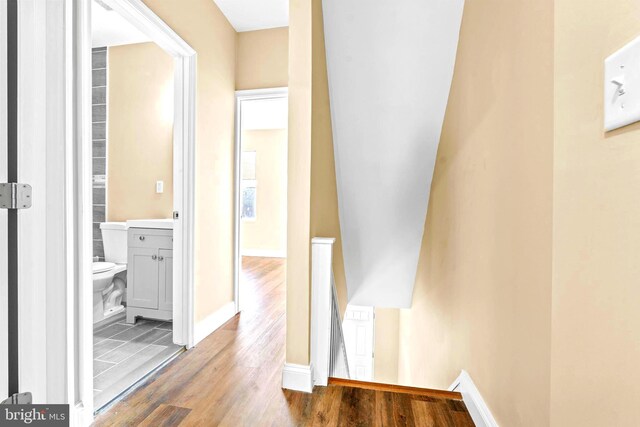 hall featuring an upstairs landing, wood finished floors, and baseboards