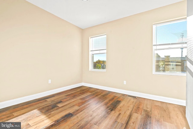 empty room featuring baseboards, visible vents, and wood finished floors