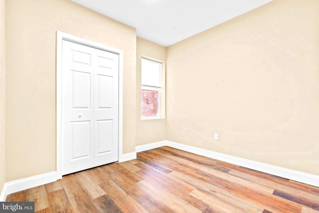 unfurnished bedroom with baseboards, light wood-type flooring, and a closet