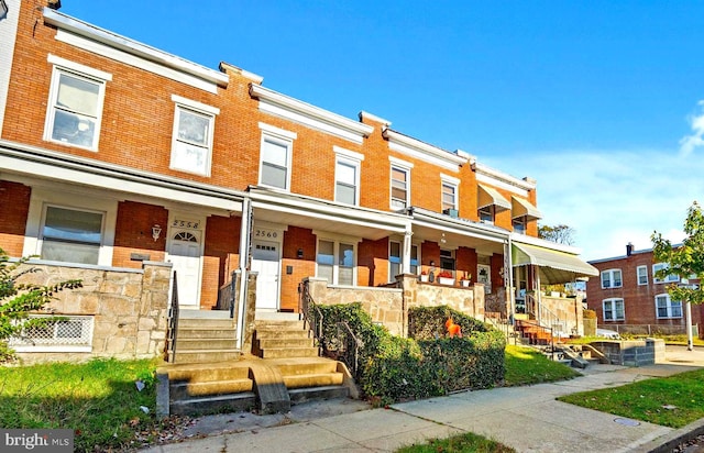 multi unit property with a porch and brick siding