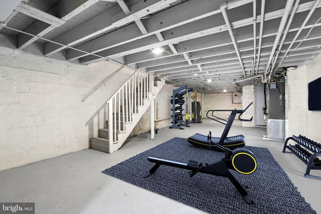 exercise room featuring heating unit, electric panel, and water heater
