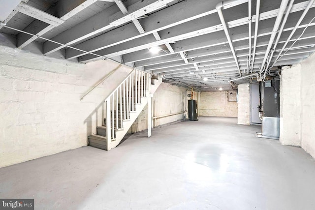 unfinished below grade area featuring water heater, heating unit, and stairway