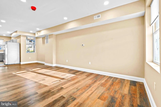 basement featuring wood finished floors, freestanding refrigerator, and baseboards